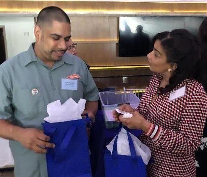 Male Employee and Female each Holding Blue Bags