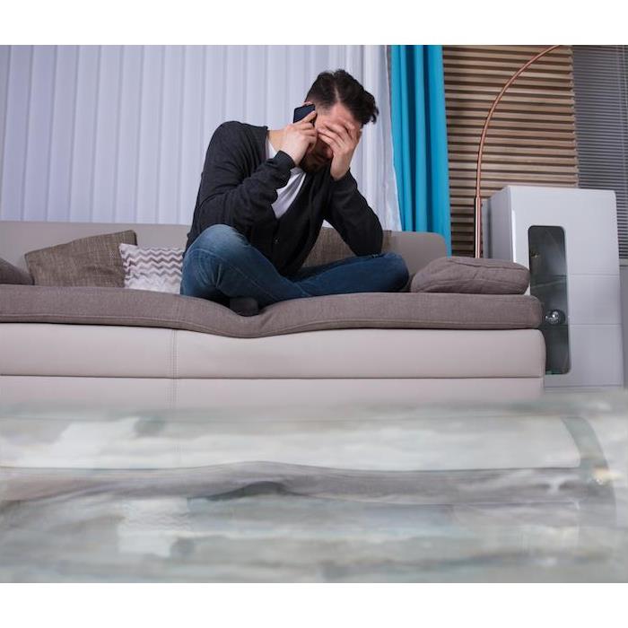 Man on phone sitting on couch submerged in water 
