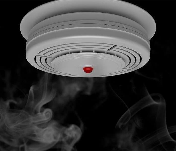 "smoke detector hanging from ceiling surrounded by smoke"